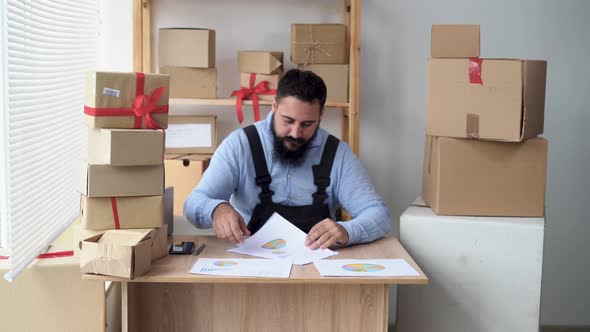 Adult Indian Businessman Working in Home Office and Looking at Sales Graph alt