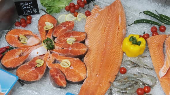Composition of Trout and Salmon Steaks Lies on Ice in Showcase of Supermarket alt