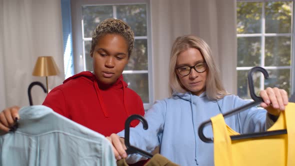 Two Diverse Girlfriends Choosing Cloths at Home Preparing for Party alt