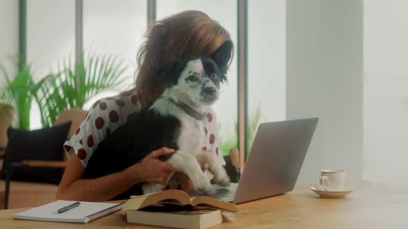 Happy Woman Typing on Laptop Along with Her Cheerful Dog Have Fun Time alt