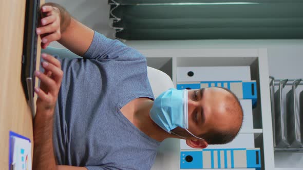 Vertical Video: Man with Maks Typing on Computer alt