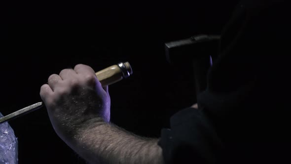 Ice Flakes Flying Around While an Artist is Using a Hammer and Chisel alt