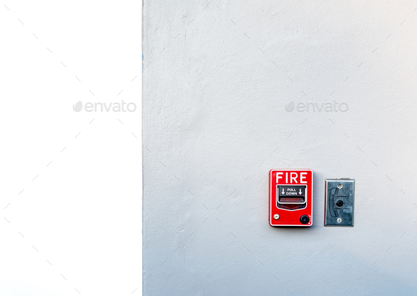 Fire alarm on white concrete wall. Warning and security system. Emergency equipment for safety alert