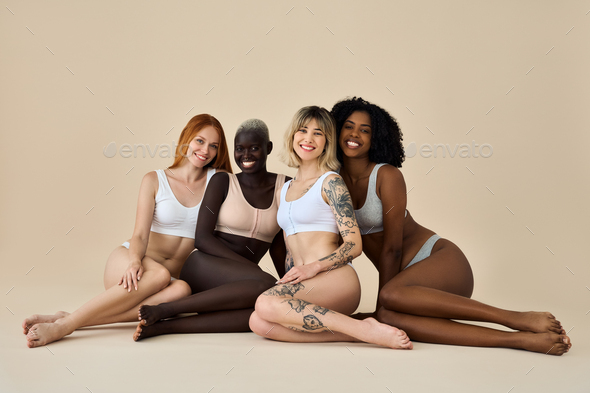 Happy diverse young women wear underwear sitting showing legs on  background. Stock Photo by insta_photos
