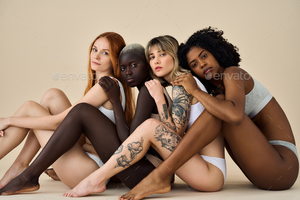 Diverse young women wear underwear sitting showing legs on beige