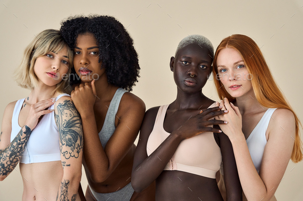 Young diverse women wearing underwear standing on beige showing
