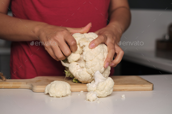 Feminine fingers snap fresh cauliflower into pieces, a culinary canvas forms. Dive into the home