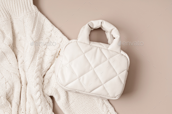 Beige quilted puffed bag and woolen accessories on pastel background