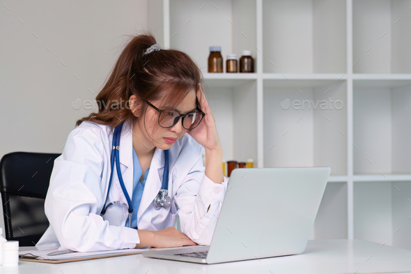 Stressed young female doctor looking at laptop, work related chaos, worried about mistake at work