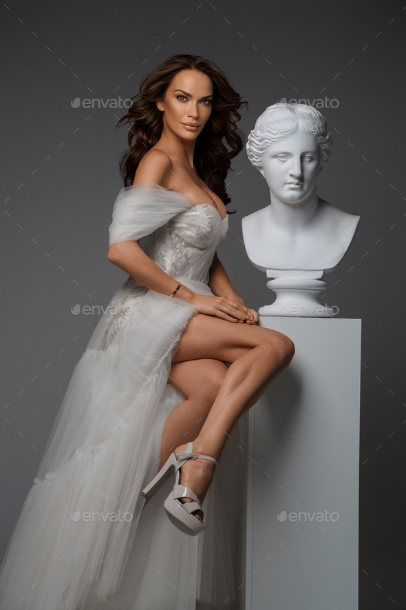 the bride in a white evening dress poses with the groom with a beautiful  hairstyle, the groom gently wraps the bride and leans against her. Portrait  photo - Stock Image - Everypixel