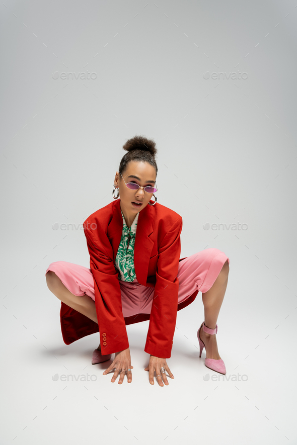 personal style, african american woman in modern attire and pink high heels posing on grey backdrop