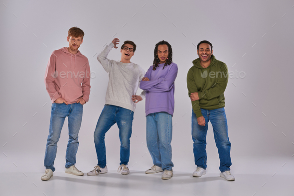 four young multicultural man in casual outfits standing and laughing at camera, cultural diversity
