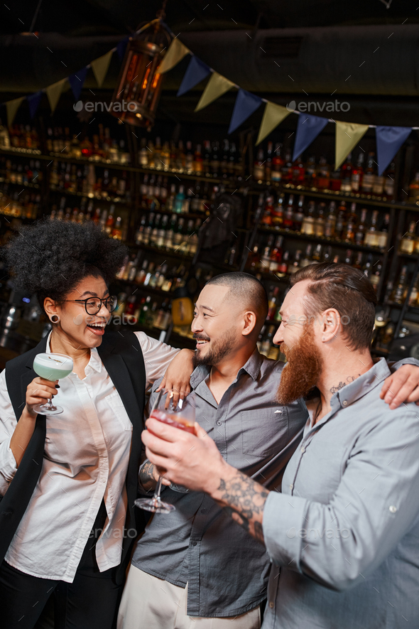 multiethnic bearded men looking at laughing african american woman during after work party in bar
