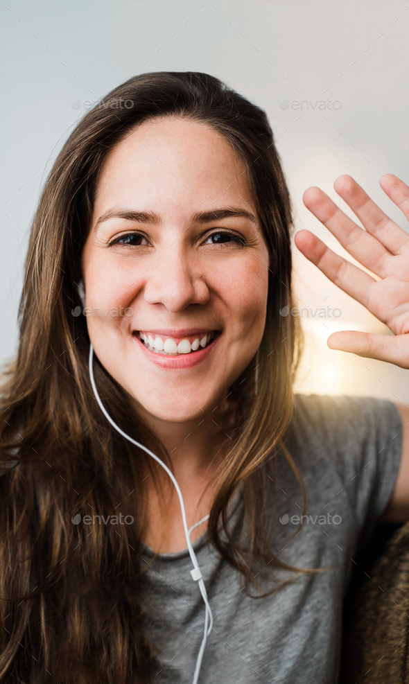Hispanic woman smiling on video call with mobile phone at home. girl streaming live on social app