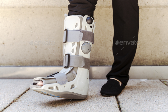 Close up of the person with broken feet in grey protecting plastic boot from ankle brace injury