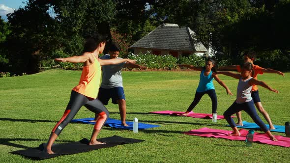 Yoga instructor instructing children in performing exercise alt