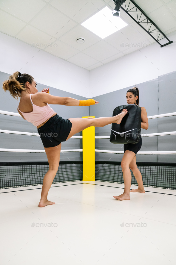 Kickboxer doing a front kick during a practice with her colleague at the gym