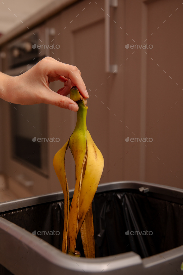 Woman putting banana peel in a trash bin. Kitchen and home Stock Photo