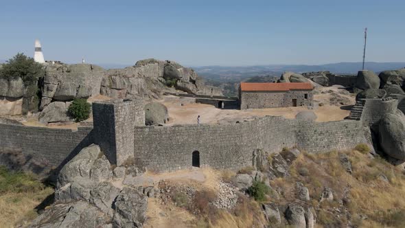 Tourist woman greeting from Monsanto castle ruins in Portugal. Aerial backward alt