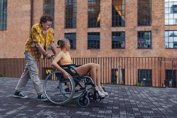 Beautiful gen Z girl in wheelchair with her boyfriend. Inclusion, equality, and diversity among
