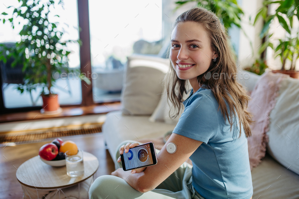 Woman with diabetes using continuous glucose monitor. Diabetic woman connecting CGM to smartphone to