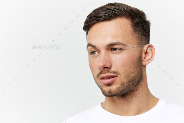 Closeup portrait. Flirted tanned handsome man in basic t-shirt raises eyebrow look aside posing