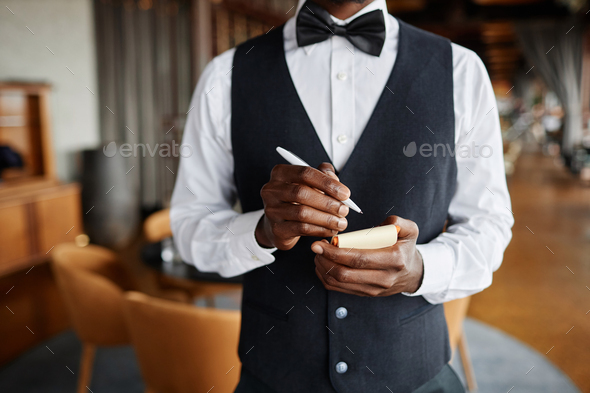 Close up of elegant server in restaurant holding notepad ready to take orders