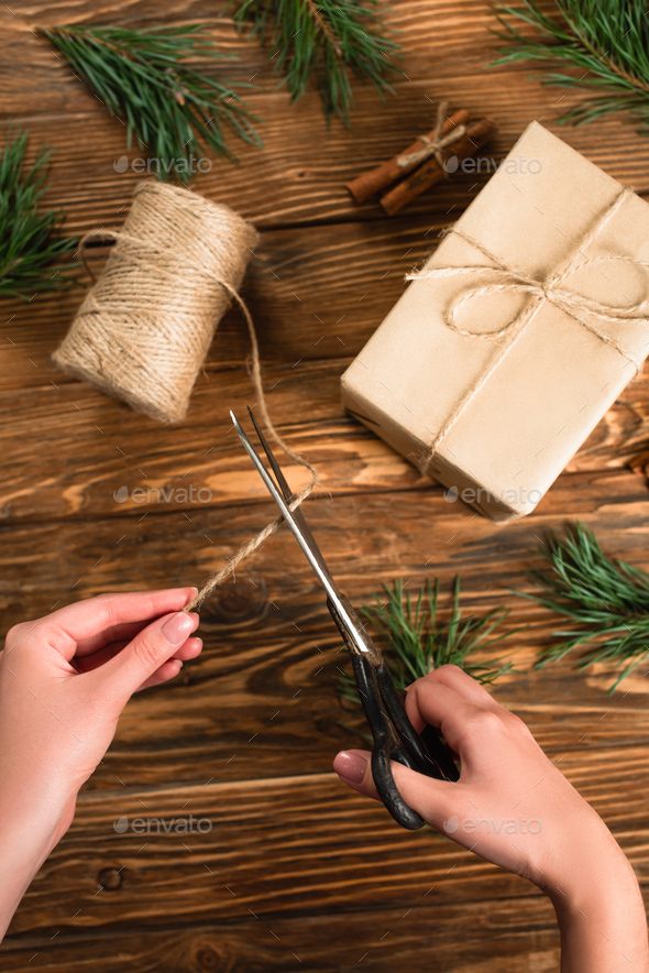 top view of green wrapping paper, scissors and present with red ribbon on  wooden background Stock Photo by LightFieldStudios