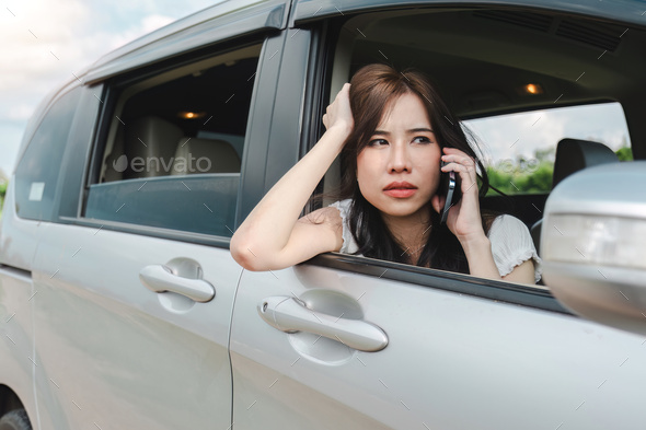 Stressed and confused Asian woman calls insurance on faulty car while traveling together