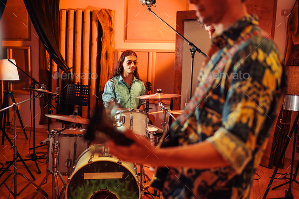 Musicians in a studio jam session, drummer playing drums.