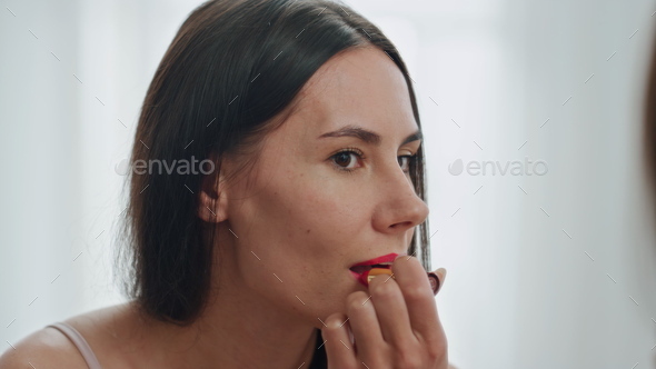 Happy girl makeup routine bathroom closeup. Woman applying red lipstick visage