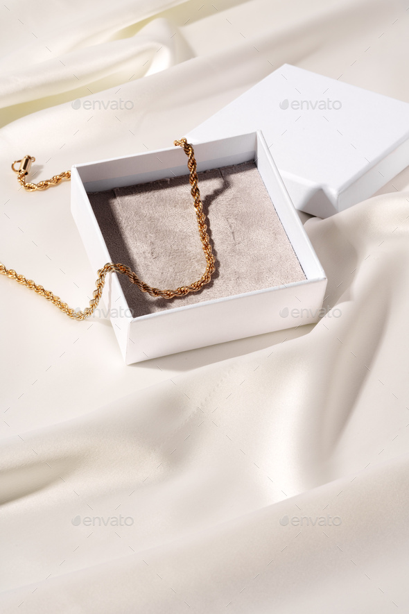 Golden chain in jewel box on silk background