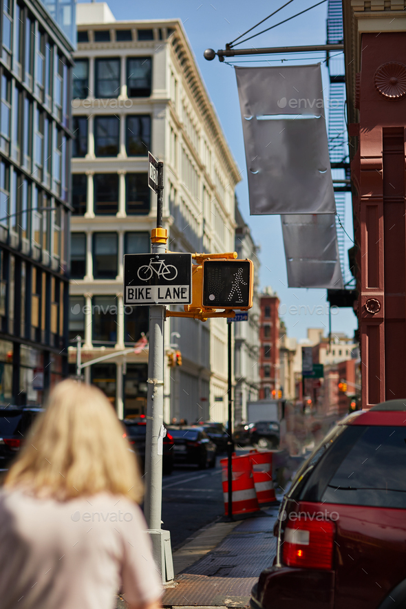 back view of blurred pedestrian on street with bike lane sign and traffic lights in new york city