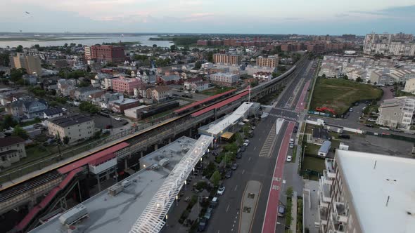 An aerial view over Arverne, NY by an elevated train station and an empty road. The camera truck rig alt