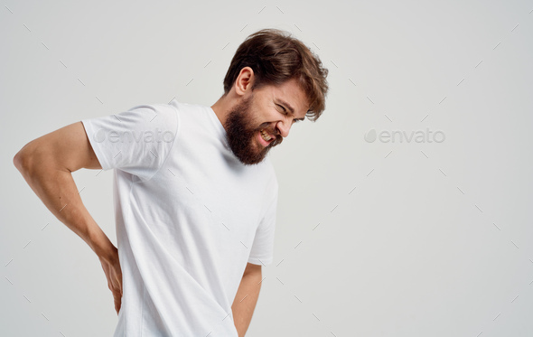 a man touches his back with his hand pain in the spine feeling unwell