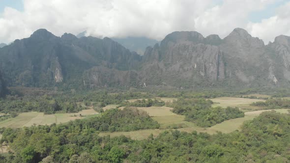 Aerial: flying over scenic cliffs rock pinnacles tropical jungle rice paddies va