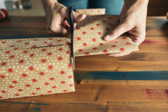 Person cutting paper with scissors to wrap a gift Stock Photo by AmparoGV
