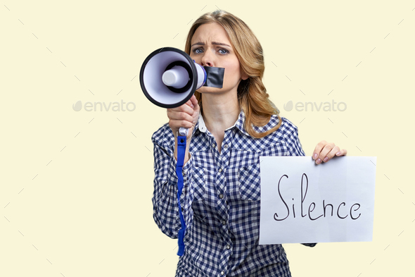 Young blonde woman struggles to speak in megaphone because of mouth taped.