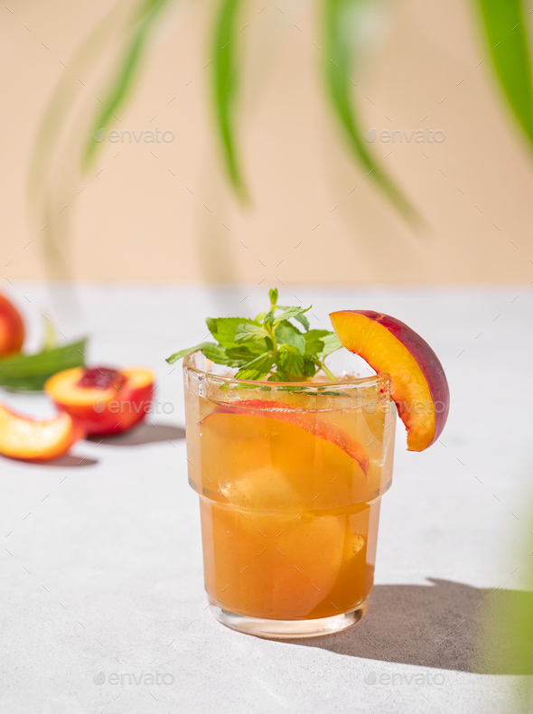 Peach tea with ice and mint. Homemade cold healthy vegetarian drink on a light background