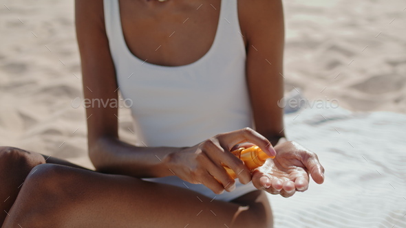 Hands spray sun protection oil closeup. Attractive girl sunbathing at seashore