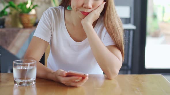 Bored asian woman looking disappointed at her smart phone while waiting someone alt