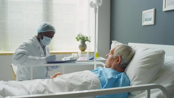 Doctor in Protective Uniform Working with Elderly Patient alt