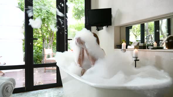 Beautiful Young Girl Having Fun in Bathtub and Blowing Foam alt