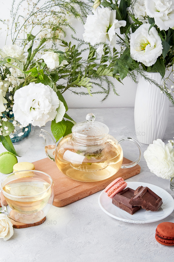 Morning table setting. Green tea, macaroon desserts, chocolate, white flowers - time for yourself