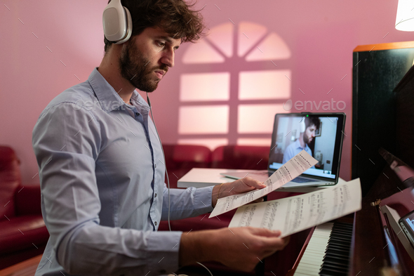 Man teaching piano lessons sheets with remote computer video call