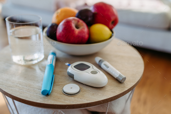 Close up of diabetes supplies and devices on table. Continuous glucose monitor, insulin pen, blood