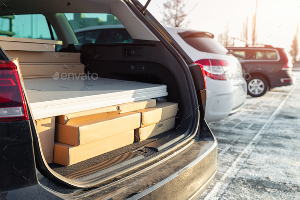 Modern black car wagon with open boot trunk back door fully loaded with furniture cardboard box