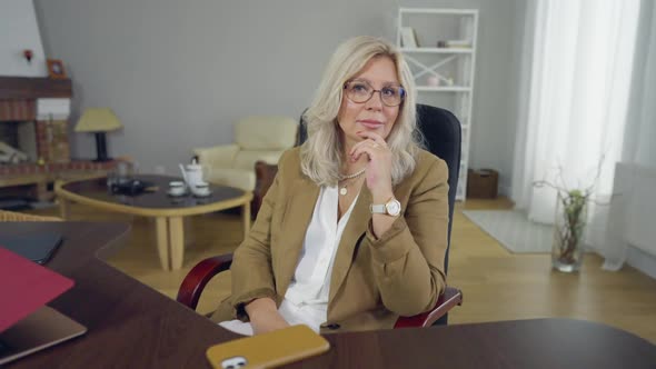 Portrait of Confident Smiling Female Psychologist Sitting at Table Looking at Camera alt
