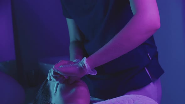 Blonde Young Woman Massagist Doing a Face Massage Using Her Fingers on Her Female Client Neon alt