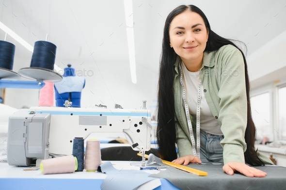 Portrait of a beautiful seamstress carrying a tape measure and